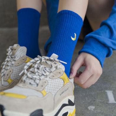 Collage of people wearing colorful socks with various designs, paired with sneakers on a tiled floor.