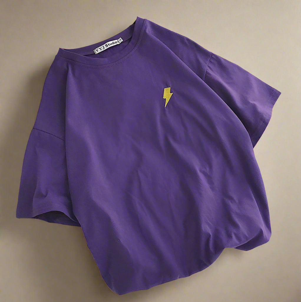 Purple t-shirt with a yellow lightning bolt on a white surface