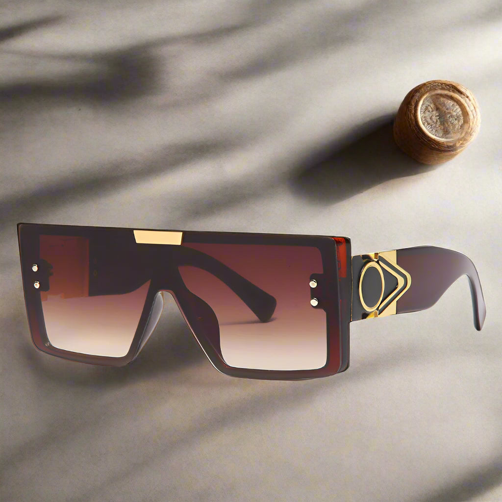 Sunglasses with a gradient lens and gold accents on a white background