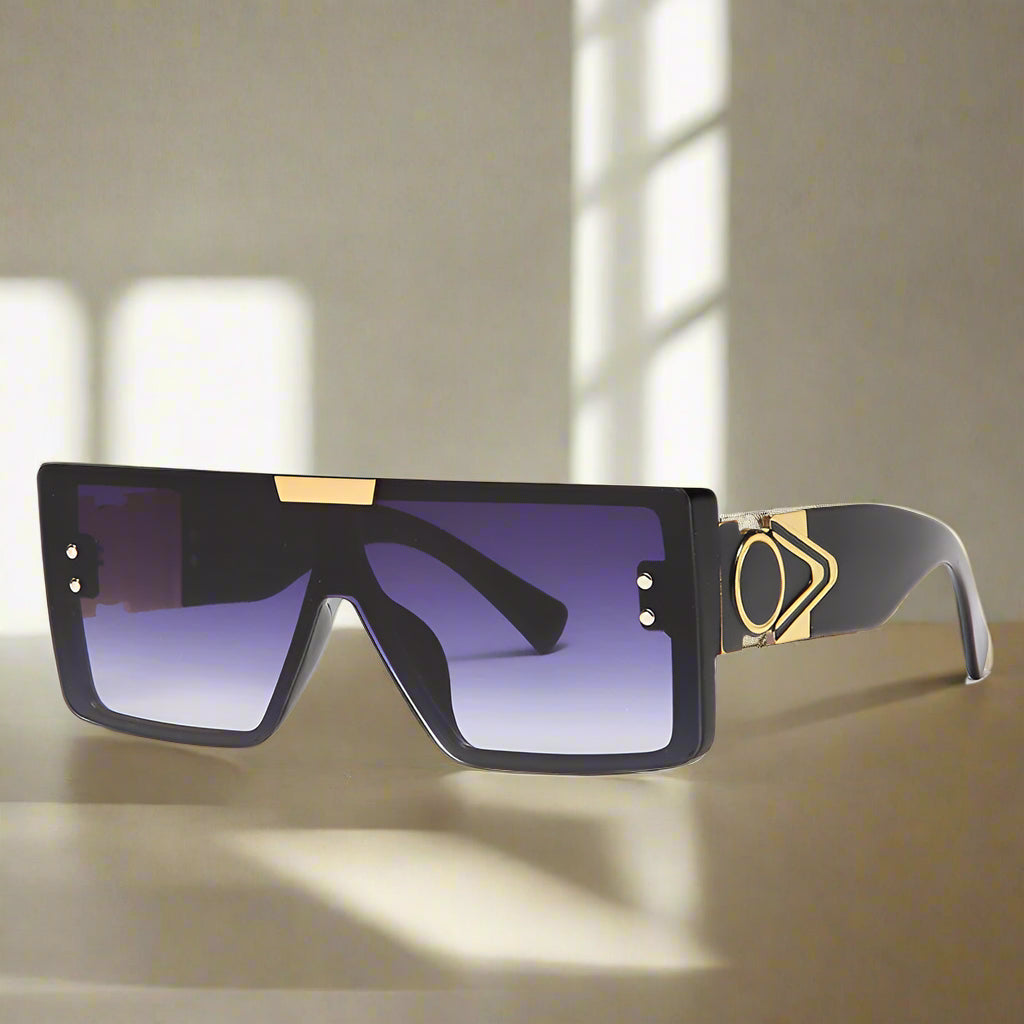 Black and gold sunglasses with gradient lenses on a white background