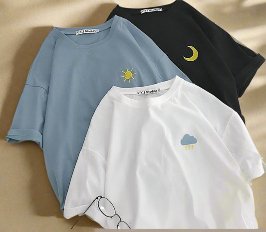 Three t-shirts with embroidered designs on a white surface.
